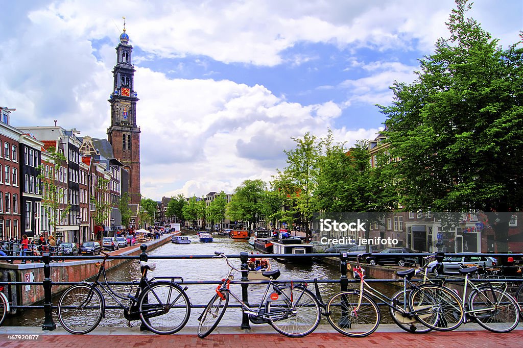 Amsterdam canal scene with church and bicycles Bicycles lining a bridge over the canals of Amsterdam, The Netherlands Amsterdam Stock Photo