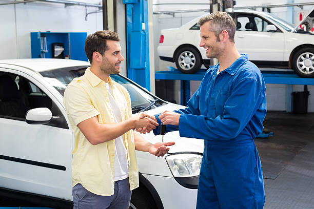 o cliente dar um aperto de mão com o mecânico tomar teclas - auto repair shop adult auto mechanic blue imagens e fotografias de stock