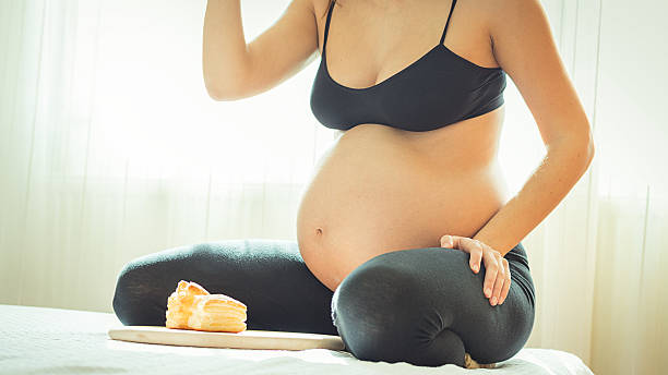 istock Women with maternity belly eating on her bed 467922652