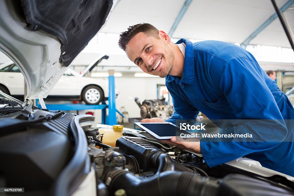 Mechanic using tablet on car Mechanic using tablet on car at the repair garage Mechanic Stock Photo