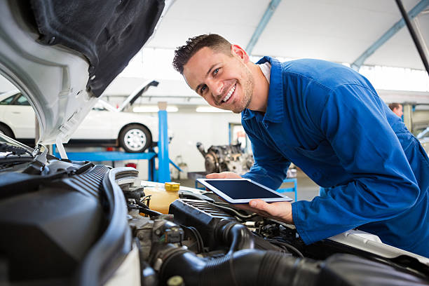Mechanic using tablet on car Mechanic using tablet on car at the repair garage bonnet hat stock pictures, royalty-free photos & images