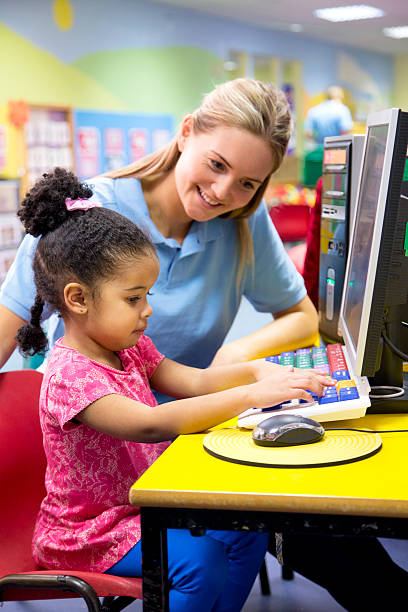 istock Little girl at nusery learning new technology with teacher. 467924112