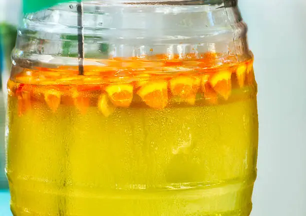 A glass jug of lemonaide with orange wedges floating on the surface