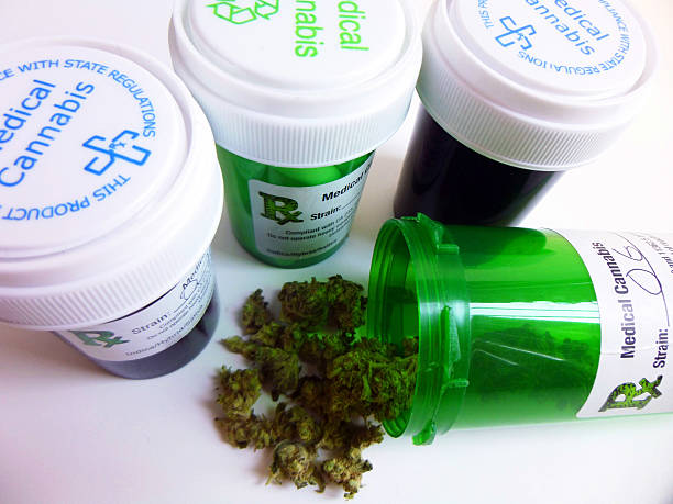 Medical Marijuana Close-up of four medical marijuana prescription containers. One opened container is in the foreground with cannabis bud falling out. medical cannabis stock pictures, royalty-free photos & images