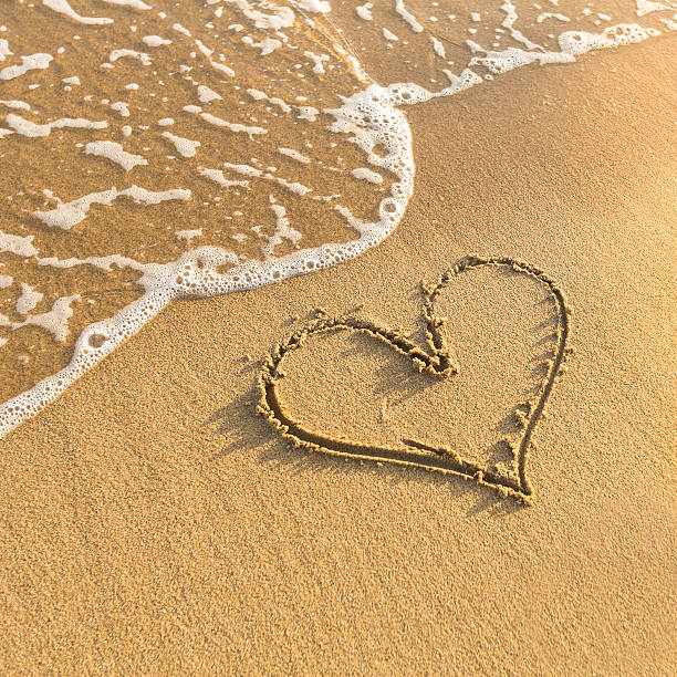 istock Heart drawn in beach sand, gentle surf wave. 467943758