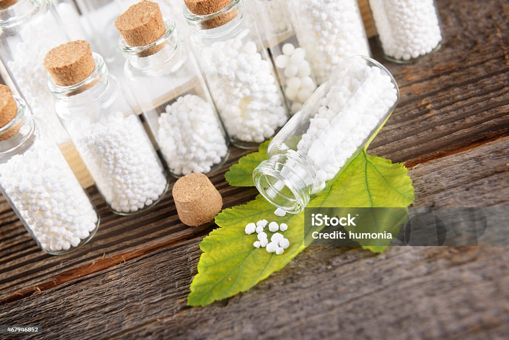 Homeopathic globules Homeopathic lactose sugar globules on leaf with glass bottle 2015 Stock Photo