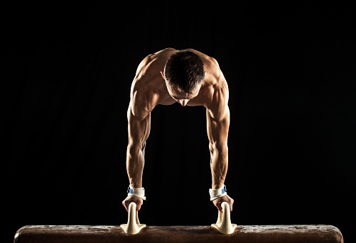 Male Gymnast doing handstand on Pommel Horse