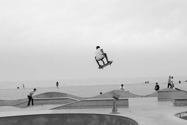 talentierten junge skateboarder in der luft schwebend in venice beach skate park - extreme skateboarding action balance motion stock-fotos und bilder