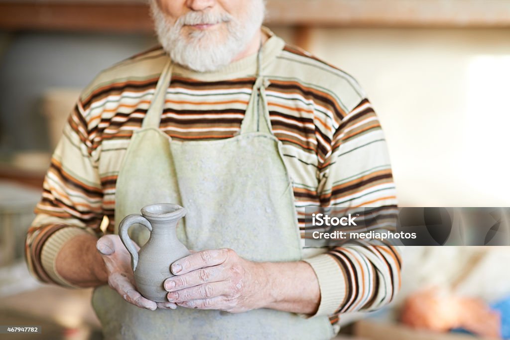 Small pottery vase Senior potter holding clay jug 2015 Stock Photo