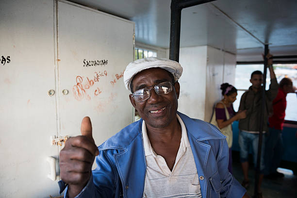 Cuban man giving thumbs up on ferry in Havana Harbor Havana, Cuba - December 17, 2014: On the day the presidents of Cuba and the United States announced their aim to restore full diplomatic ties, a Cuban man gives a thumb up when he says hello to a photographer on a ferry in Havana Harbor, traveling from the neighborhood of Casablanca to Habana Vieja. havana harbor photos stock pictures, royalty-free photos & images