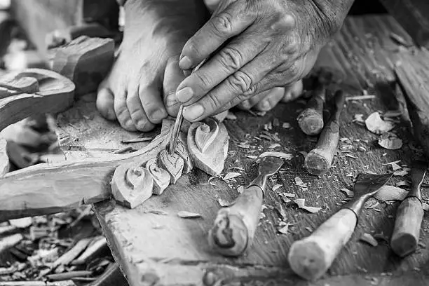 Photo of Hand of carver carving wood in blackand white color tone