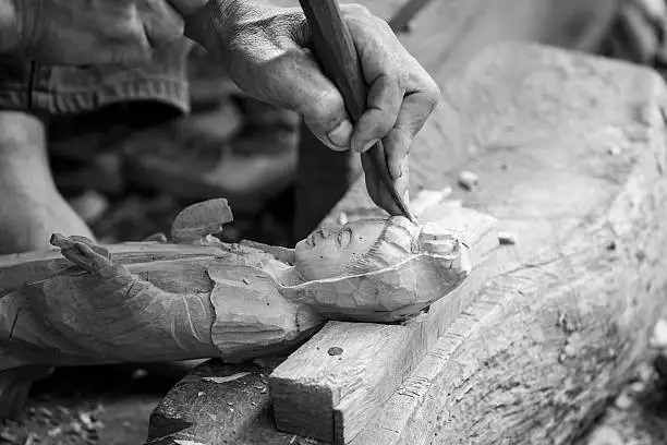 Photo of Hand of carver carving wood in blackand white color tone