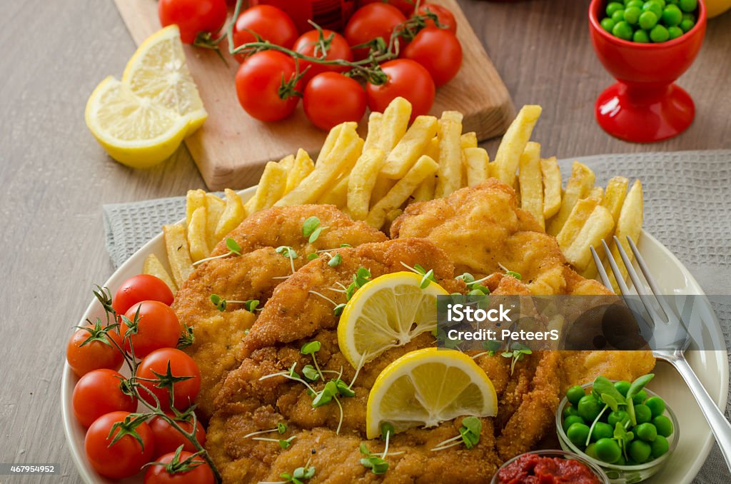 Schnitzel, french fries and microgreens salad Schnitzel, french fries, cherry tomatoes and fresh microgreens pea salad 2015 Stock Photo