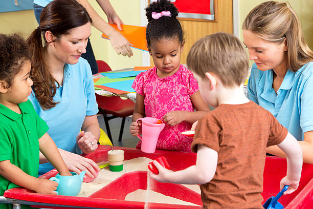 istock Nursery workers with children playing in the sandpit 467955128
