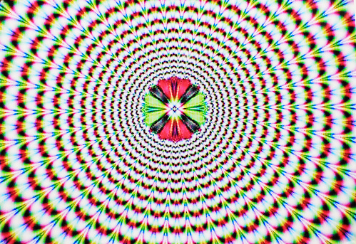 Digital abstract image with an explosion of blue red yellow green and purple producing an optical illusion of movement.
