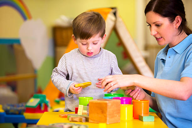 istock Little boy and nursery teacher playing with building blocks 467960232