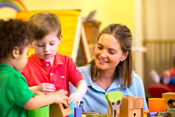istock Nursery teacher supervising children playing with building blocks 467960248
