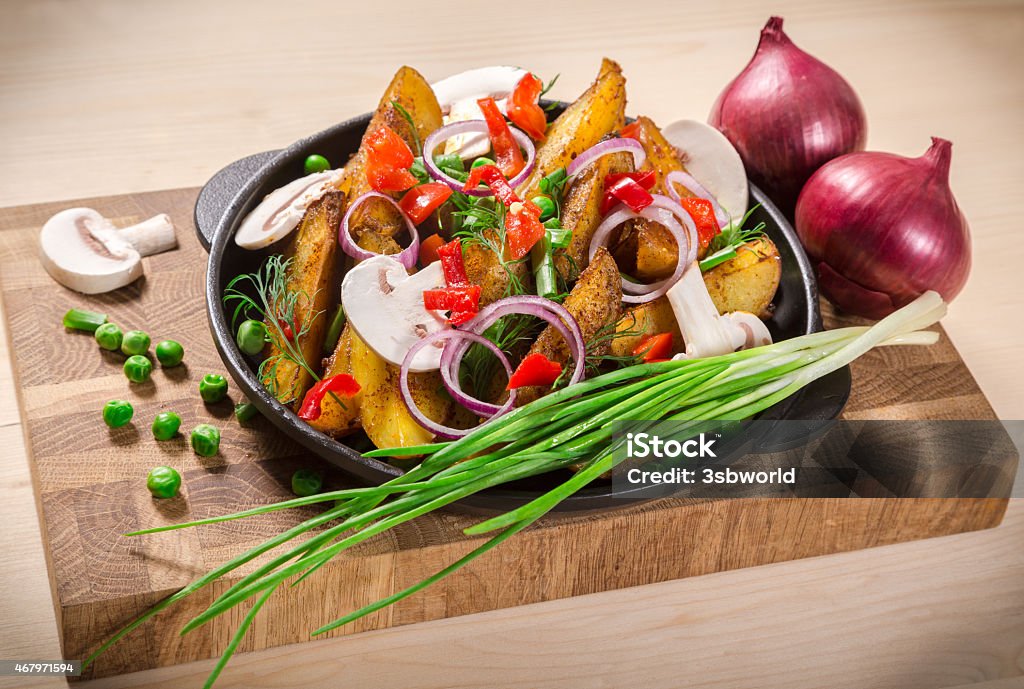 baked sliced potatoes on pan baked sliced potatoes with vegetables and mushrooms on frying pan 2015 Stock Photo