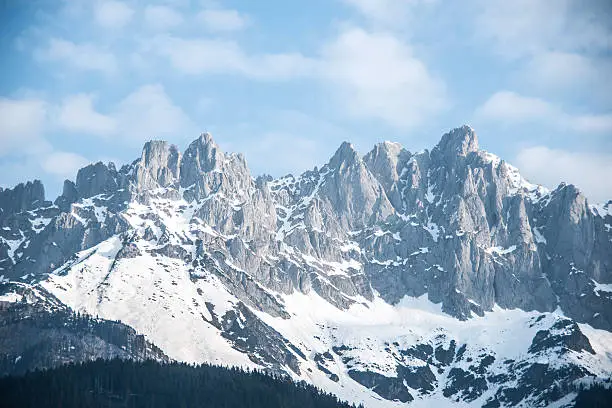 Skier on snowy hill peak in austria kitzbuehel Wilder Kaiser. Blue sky and many copyspace.