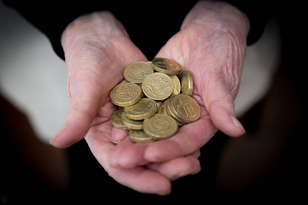 高齢者の手を保持英ポンドの硬貨 - one pound coin coin currency british culture ストックフォトと画像