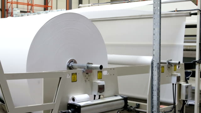 Big roll of paper turning on spindle in manufacturing