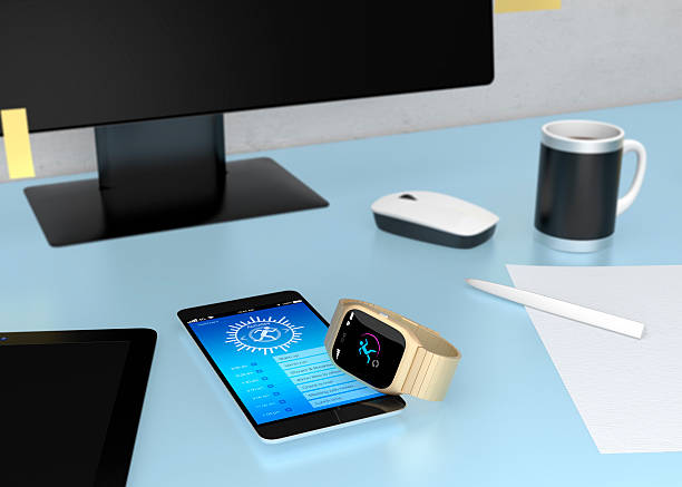 Smart watch synchronizing fitness app with smart phone on table.