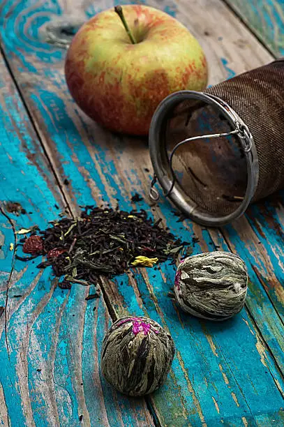 tea leaves and red apple on wooden background.The image is tinted in vintage style
