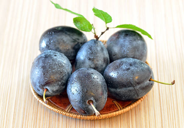 istock Rip plums on basket on wooden table 467982311