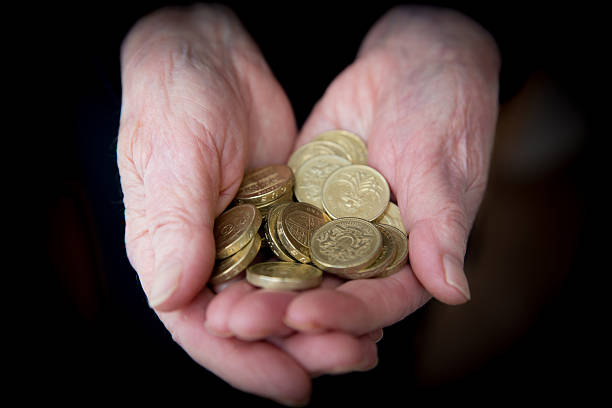 高齢者の手を保持英ポンドの硬貨 - one pound coin coin currency british culture ストックフォトと画像