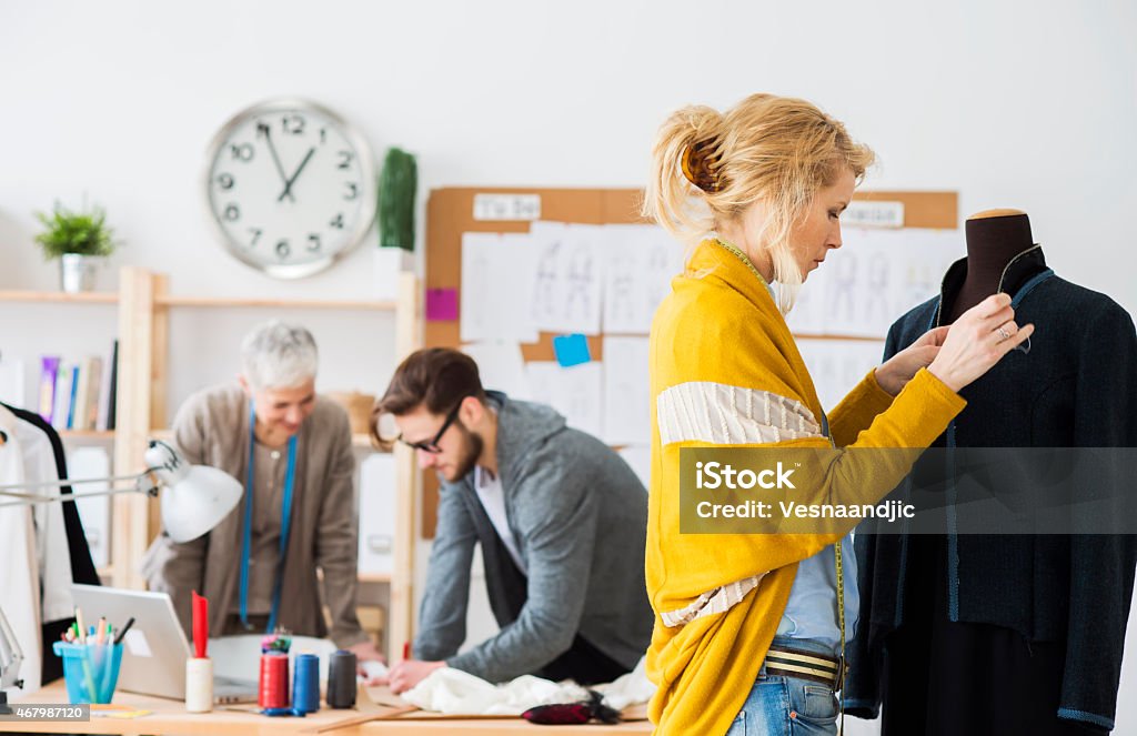 Fashion designers Fashion designers working together in studio, young woman working on new jacket 2015 Stock Photo