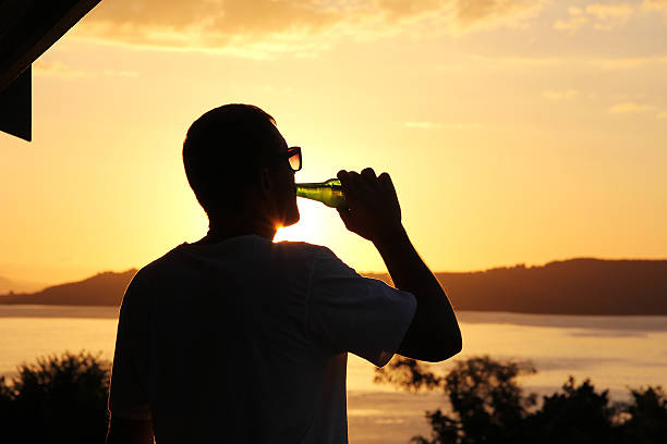 Silhouette of a man at sunset with a bottle of beer in his hand