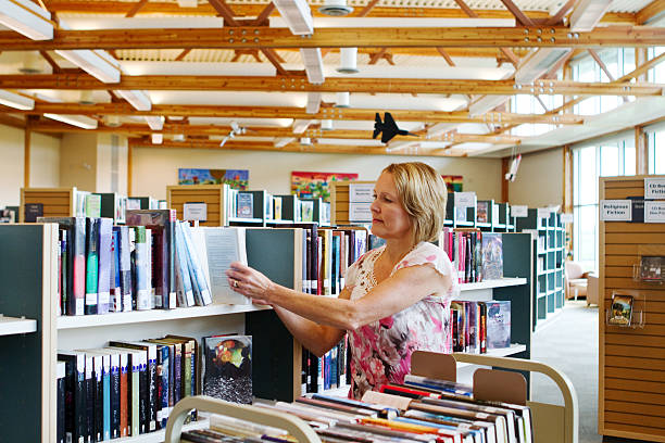 Librarian replacing books on shelves Librarian replacing books that have been borrowed librarian stock pictures, royalty-free photos & images