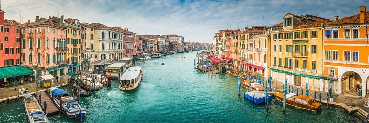 The Grand Canal busy with local boats working the crowded waterway between characteristic stucco villas and restaurants, hotels and gondolas in the heart of this iconic Italian city. ProPhoto RGB profile for maximum color fidelity and gamut.