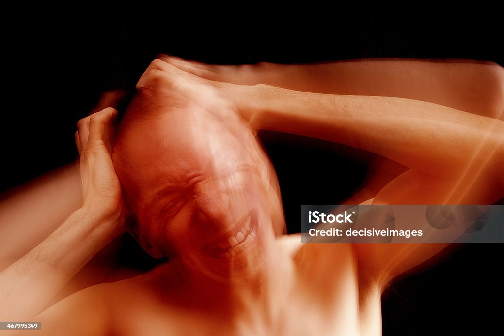 Migraine headache A man expressing despair and pain, holding his hands to his head. Shot with deliberate motion and flash blur. Adult Stock Photo