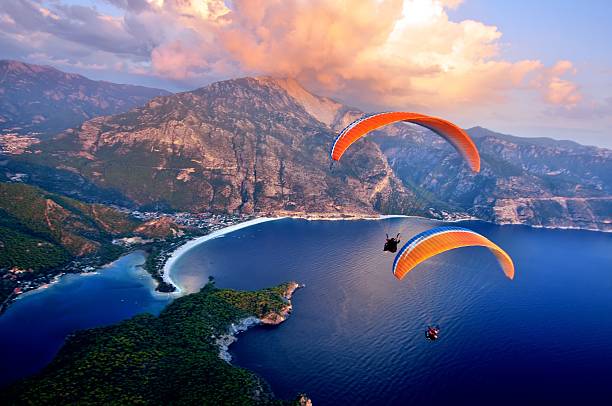 Paragliding into the sunset over the ocean Oludeniz beach, Fethiye, Turkey paraglider stock pictures, royalty-free photos & images