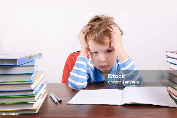 Tired Boy Sitting At A Desk Holding Hands To Head Stock Photo - Download Image Now - 6-7 Years, Adversity, Child