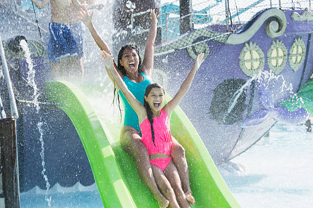 istock Mother and daughter going down water slide 468000116