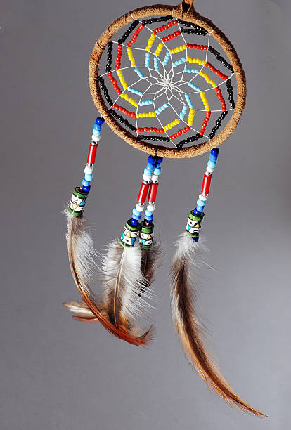 Dream Catcher Tight shot of beaded Native american dream catcher on gray background. symbol north american tribal culture bead feather stock pictures, royalty-free photos & images