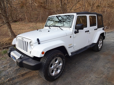 Potomac, USA-March 26, 2015: This white Jeep Wrangler Sahara was spotted at a parking lot next to the C&O canal in central Maryland. The Jeep is powered by a 285 HP V6 Pentastar engine and gets 16-21 MPG. Jeep makes off road vehicles suitable for outdoorsmen.  Jeeps are popular vehicles.