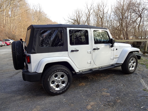 Potomac, USA-March 26, 2015: This white Jeep Wrangler Sahara was spotted at a parking lot next to the C&O canal in central Maryland. The Jeep is powered by a 285 HP V6 Pentastar engine and gets 16-21 MPG. Jeep makes off road vehicles suitable for outdoorsmen. Jeeps are popular vehicles.