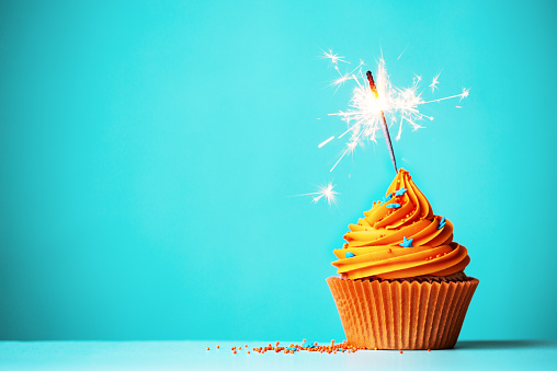 Orange cupcake with sparkler and copy space to side