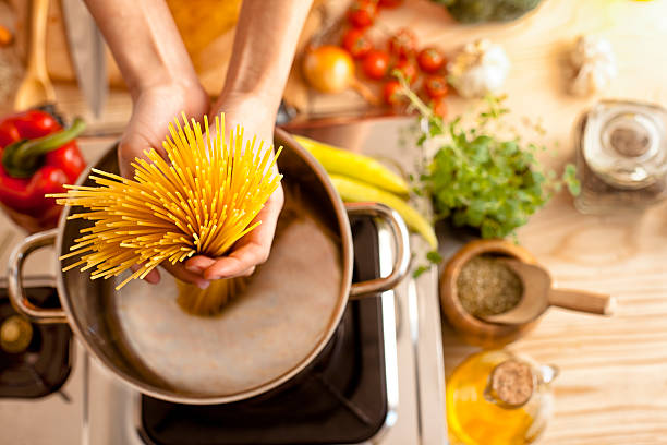 kobieta w kuchni trzymając spaghetti - chef cooking food pan zdjęcia i obrazy z banku zdjęć