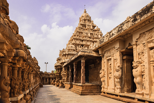 Built on the banks of the Vedavathi River, the 1300 year old Kailasanathar Temple is the oldest structure in in the Tamil Nadu city of Kanchipuram in South India.  Built by the Pallava King Rajasimha also known as Narasimhavarman II, in the Dravidian style of architecture, Carved and sculpted almost completely out of sandstone, it was built between 685 and 705 AD; it is dedicated to the god Shiva. Photo shot in the afternoon sunlight shows the circumambulatory passage of the western side; on the left is the inner side of the outer wall as well. Each of the sections houses a shrine - 58 in total. Converging lines make for an interesting photograph. Horizontal format; no people. Copy Space.