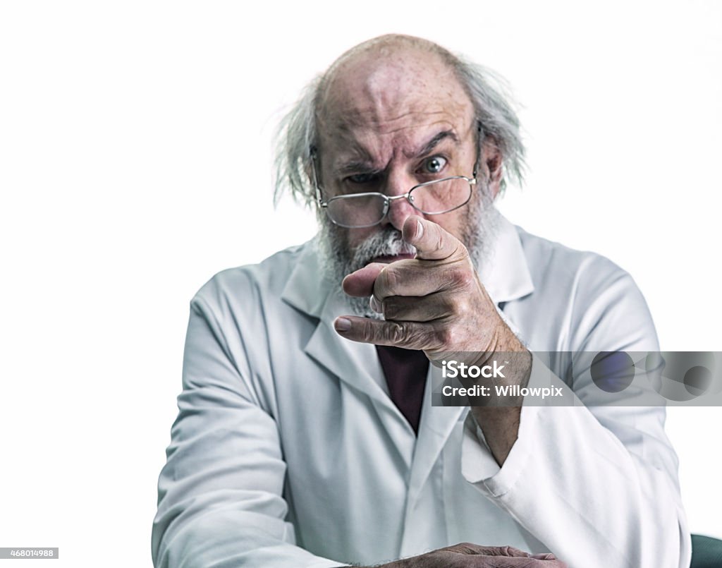 Angry Scientist With Wild Hair Pointing Finger At Camera An angry, tangled hair research scientist is pointing his index finger at the viewer. With a stern expression on his face, and one eyebrow raised, he stares over his eyeglasses directly at the camera. He is a balding senior adult man with a gray beard and mustache. He is wearing a white lab coat over his casual polo shirt. Canon 5D Mark III. Doctor Stock Photo