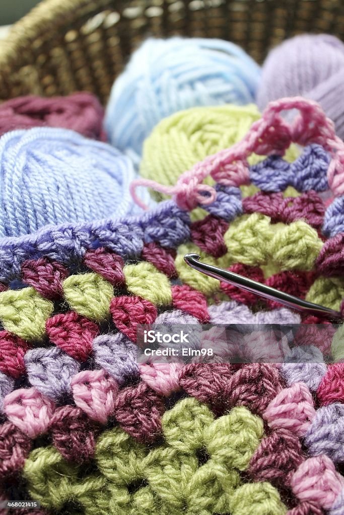 Making an afghan Crochet and balls of wool in a basket, making an afghan blanket, a traditional, vintage hobby Basket Stock Photo