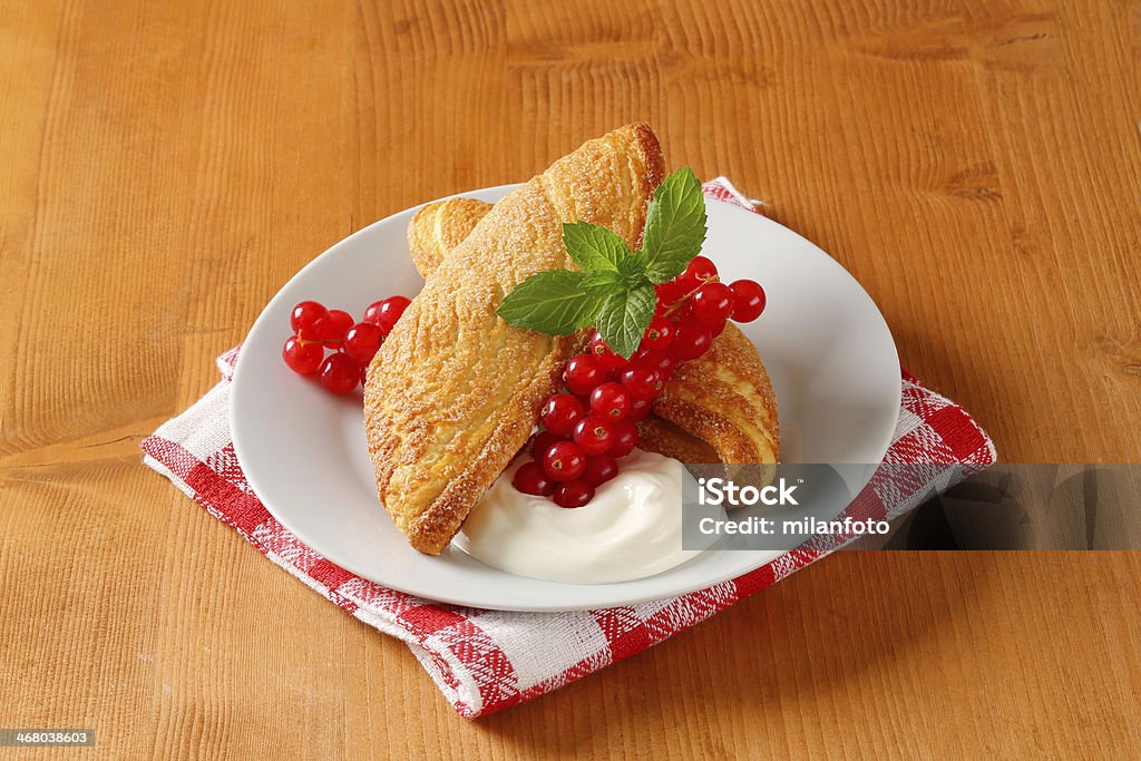 fiorentines with red currant and whipped cream phyllo pastries fiorentines with red currant and whipped cream on white plate and chequered disthtowel Apricot Stock Photo