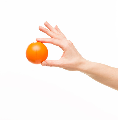 female hand holding with two fingers orange ball, isolated on white