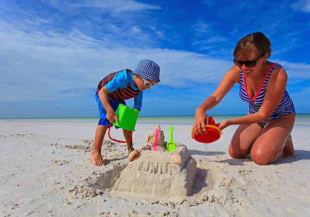 istock mother and son building sand castle on summer beach 468049210