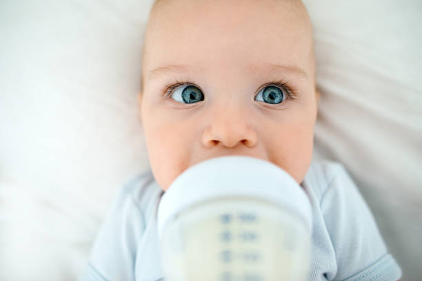 istock beautiful baby lying on his back in bed drinking milk 468060136