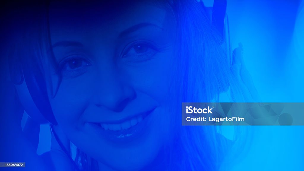 Young woman listening to the music, abstract lights background Attractive young woman listening to music with large headphones and blue bokeh light background Headphones Stock Photo